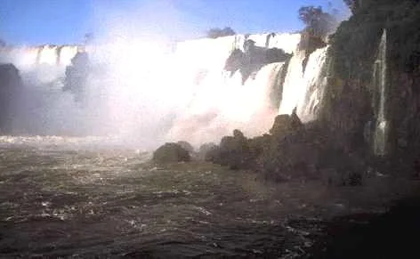 De la brume s'élève des eaux tumultueuses des chutes de l'Iguaçu, à l'extrémité nord de l'Argentine, non loin de sa frontière avec le Paraguay et le Brésil. Larges d'environ 4 km, les chutes de l'Iguaçu offrent une vu…